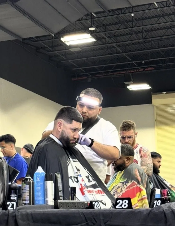 Barber cutting a client's hair on a busy barber competition floor